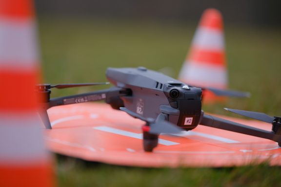 Ein Drohne landet auf einem orangefarbenen Ziel, umgeben von roten Markierungskegeln.